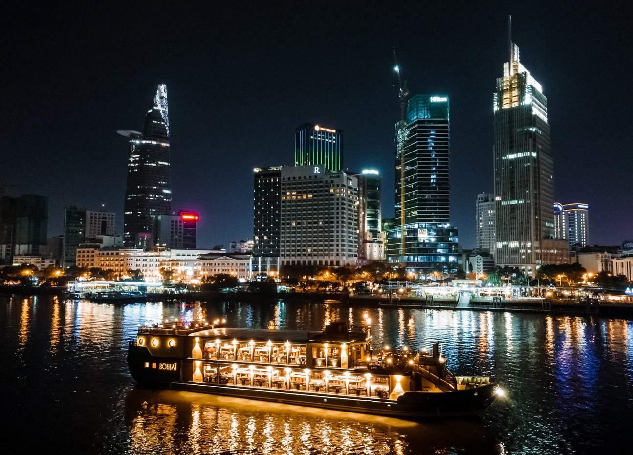 Dinner cruise along Saigon River with city skyline at night.