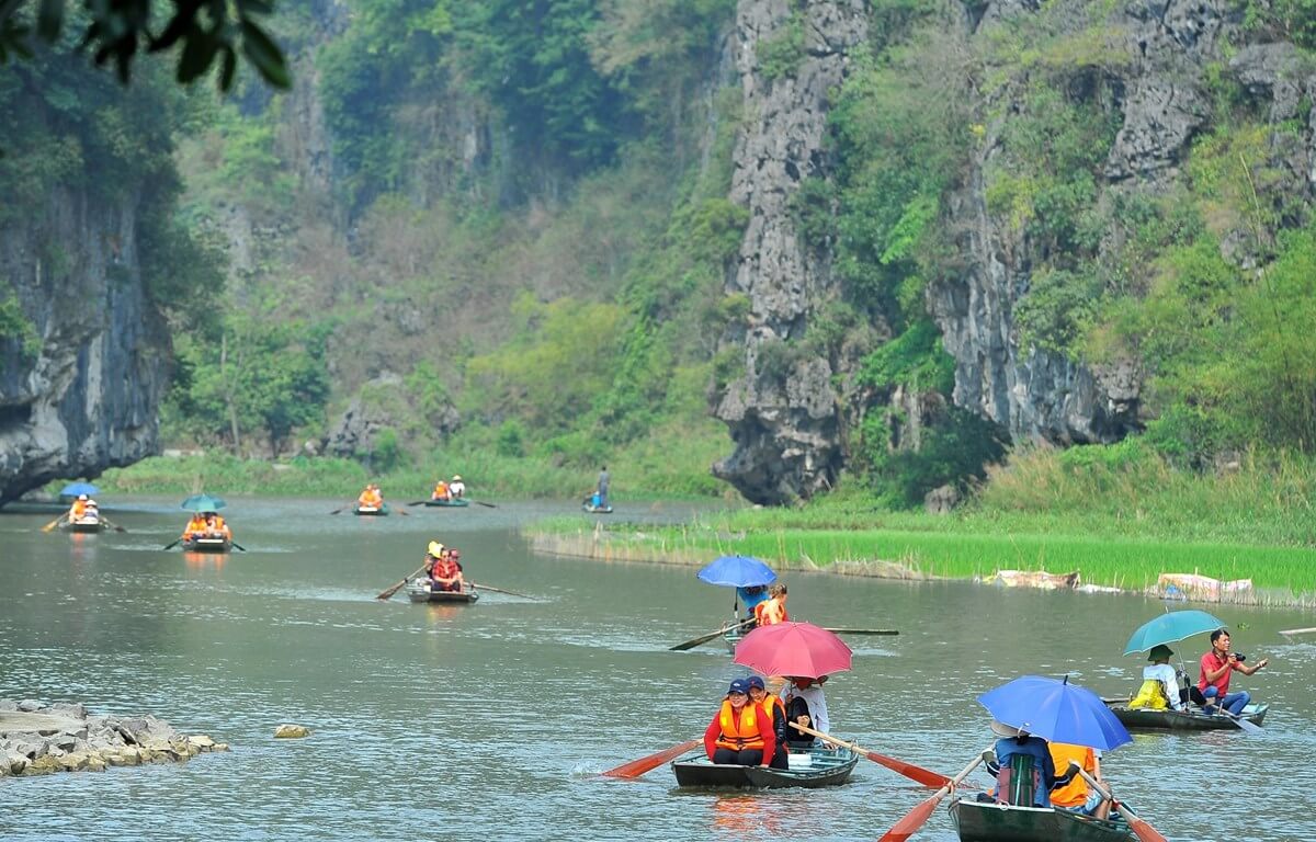 Rowboat passing through limestone karsts along Ngo Dong River in Tam Coc, Ninh Binh.