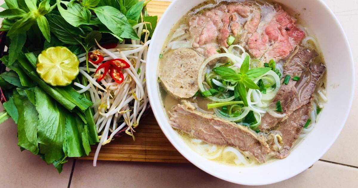 Steaming beef noodle soup with fresh herbs