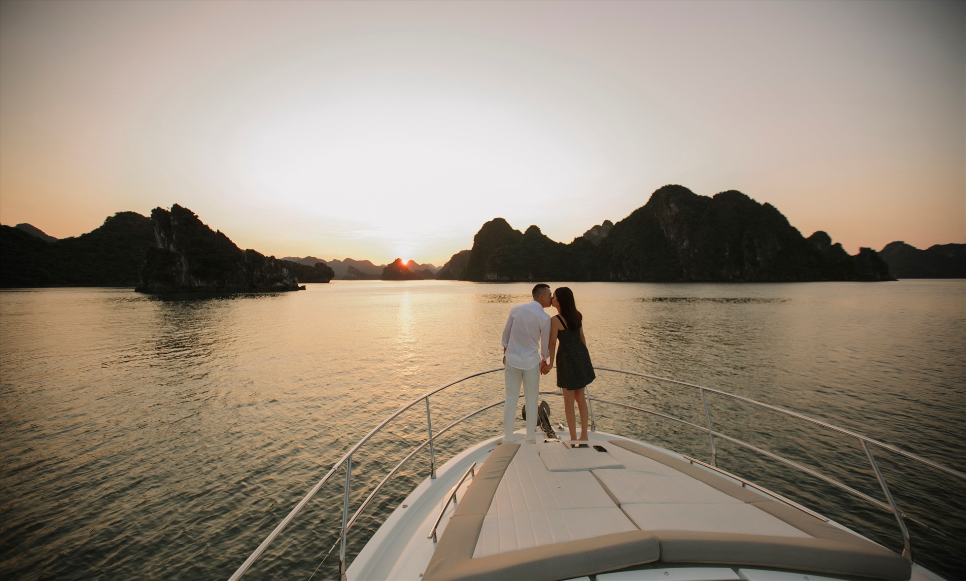 Guests relaxing on a spacious cruise deck overlooking sunset in Ha Long Bay