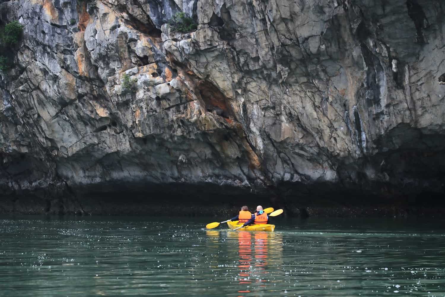 Travelers paddling kayaks through towering limestone formations