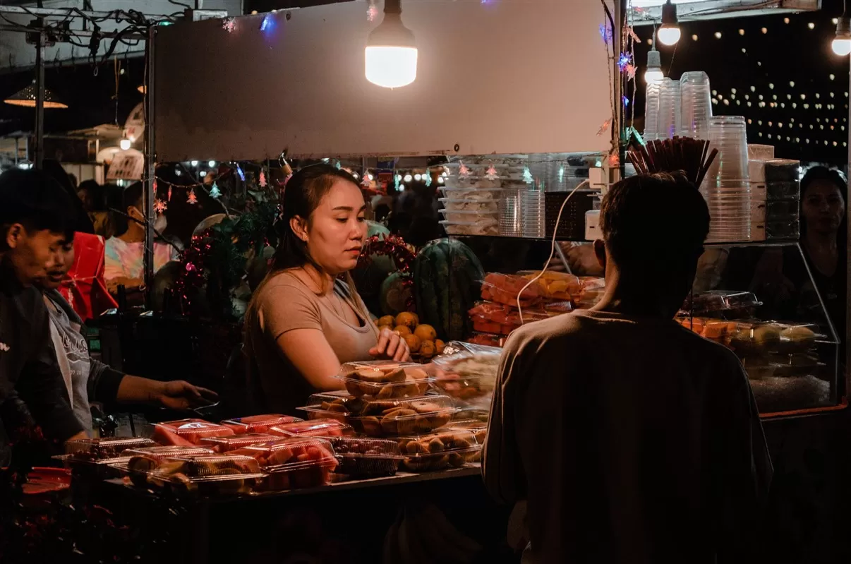 Street food vendors serving local dishes in a lively night market setting